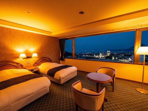 别府Yukai Resort Premium Hotel Fugetsu的酒店客房设有两张床和大窗户。