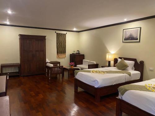 琅勃拉邦Luang Prabang Residence & Travel的酒店客房带两张床和一张桌子以及椅子。