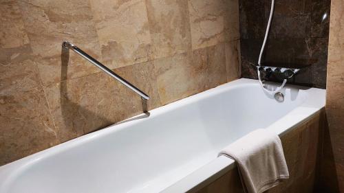 JatinangorJatinangor National Golf & Resort的浴室设有白色浴缸,配有毛巾