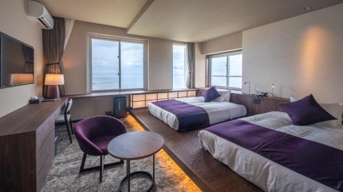 屋久岛THE HOTEL YAKUSHIMA ocean & forest的酒店客房带两张床和一张桌子以及椅子。
