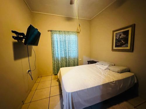科尔特斯港Casa en Puero Cortes的一间卧室设有一张床、一台电视和一个窗口。