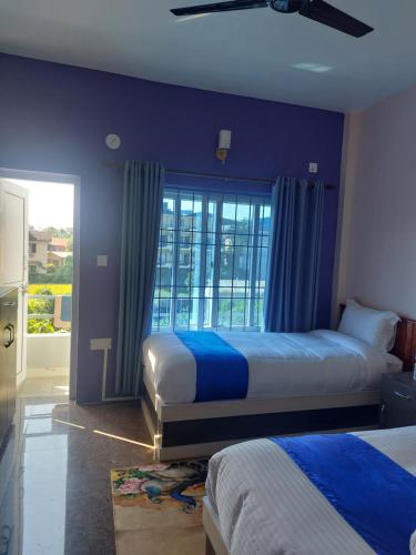 索拉哈Hotel Namo Buddha的一间卧室设有两张带蓝色墙壁和窗户的床。