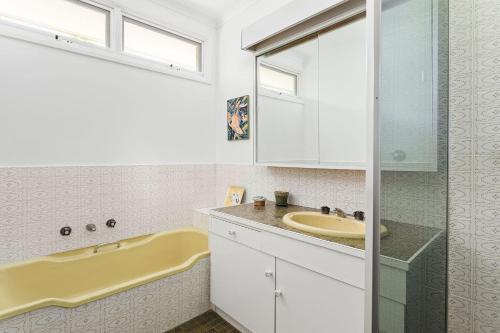 Mount WaverleyBoutique Stays - That 70s House的浴室配有盥洗盆和浴缸。