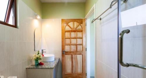 拉迪格岛Hyde-Tide Guesthouse的一间带水槽和门淋浴的浴室