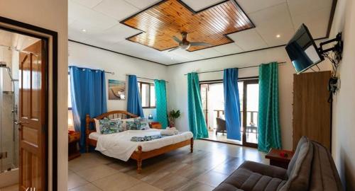 拉迪格岛Hyde-Tide Guesthouse的一间卧室配有一张带蓝色窗帘的床和电视。