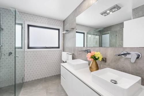 黄金海岸Luxury Modern Waterfront House的一间带两个盥洗盆和淋浴的浴室
