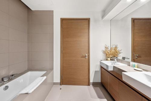 迪拜City Walk, Al Wasl, Jumeirah - Mint Stay的一间带两个盥洗盆和浴缸的浴室以及一扇木门。