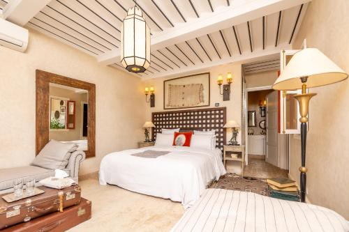 马拉喀什印度宫殿酒店的卧室配有一张白色的大床和一张沙发。