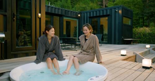 Tsuru 郷音 ～G.O.A.T～的两名妇女坐在冲浪板上,在热水浴缸中