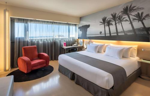 马拉加马拉加巴瑟罗酒店的酒店客房设有一张大床和一张红色椅子。