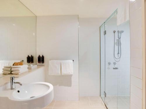 墨尔本北墨尔本美居酒店的白色的浴室设有水槽和淋浴。