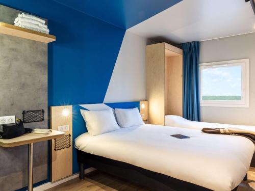 维勒蒙布勒ibis Budget Villemomble的酒店客房,设有床铺和蓝色的墙壁