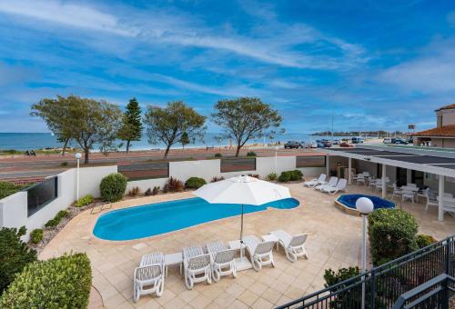珀斯索伦托海滩度假酒店的一个带游泳池、椅子和遮阳伞的庭院