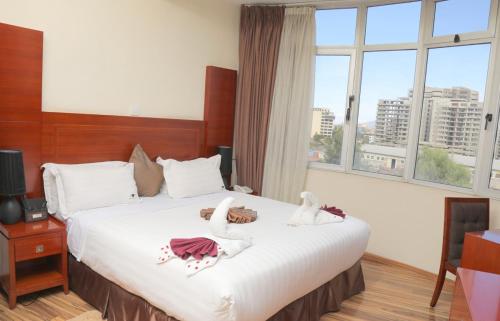 亚的斯亚贝巴Hotel Miracle的一间卧室配有一张大床,上面有两个天鹅