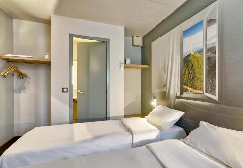 克莱蒙费朗B&B HOTEL Clermont-Ferrand Le Brézet Aéroport的一间卧室设有两张床和窗户。