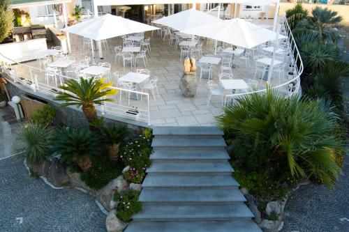 伊斯基亚Hotel Parco Delle Agavi的楼梯通往带桌子和遮阳伞的餐厅