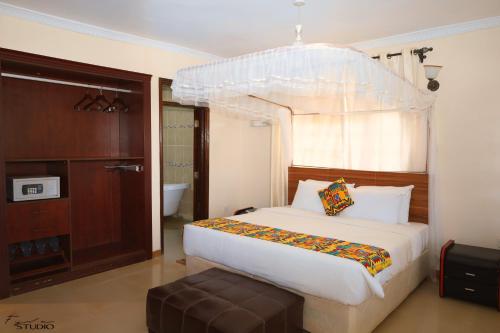 MeruGatimene Gardens Hotel的一间卧室配有一张带天蓬的白色床