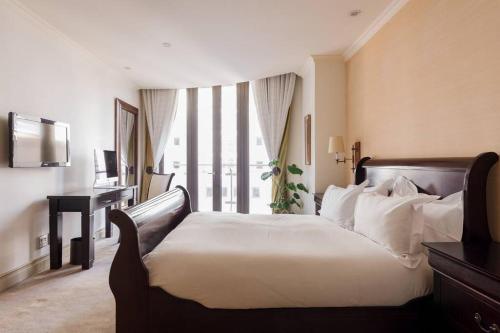 约翰内斯堡Luxury & Breathtaking Sandton & JoburgAmazing View的一间卧室配有一张床、一张书桌和一个窗户。