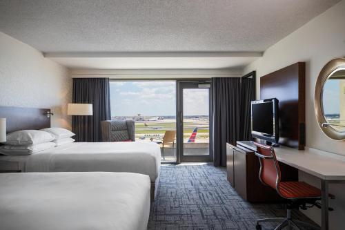 亚特兰大亚特兰大机场康考斯万丽酒店的酒店客房设有两张床、一张桌子和一台电视。