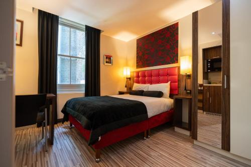 伦敦简朴客房&套房酒店的一间卧室配有一张大床和红色床头板