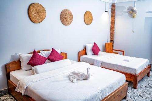 马德望Bat Rice Resort的配有粉红色枕头的客房内的两张床