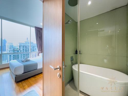 吉隆坡Soho Suites KLCC by Wakely Kuala Lumpur的带浴缸、床和玻璃门的浴室