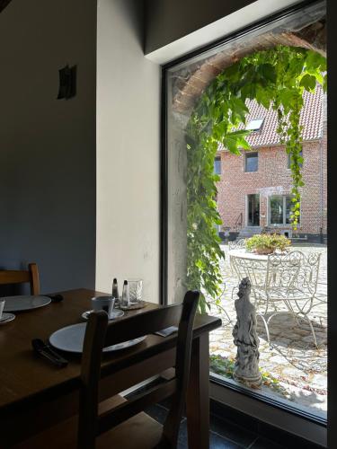 博尔赫隆De Verborgen Parel的一间带桌子和大窗户的用餐室