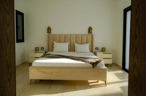 DjerbaVilla des deux oliviers Djerba的一间卧室配有一张带2个床头柜的大床
