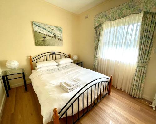 金斯科特Baywater的一间卧室配有一张带白色床单的床和一扇窗户。