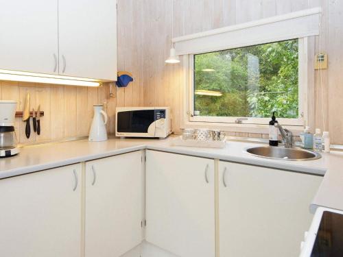 福旺Holiday home Fårvang VII的厨房配有白色橱柜、水槽和窗户。