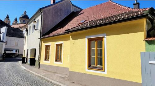 梅尔克Altstadthaus Marille mit Innenhofterrasse的街上有红色屋顶的黄色房子