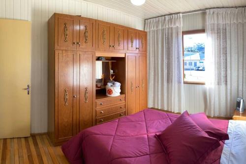 本图贡萨尔维斯Casa aconchegante no Vale Vinhedos的一间卧室配有紫色的床和木制橱柜