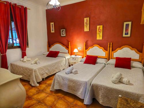 埃尔加斯托尔JARANDALUS (casa con atractivo y encanto)的红色墙壁客房的两张床
