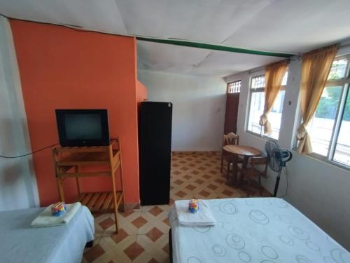 普卡尔帕LAS ORQUIDEAS Hospedaje的客房设有两张床、一台电视和一张桌子。
