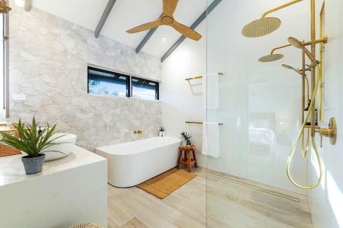 Fannie Bay'Villa Nalu' A Dreamy Fannie Bay Escape的带浴缸和玻璃淋浴间的浴室。