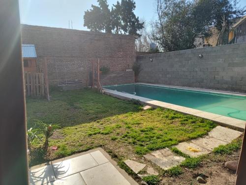 埃塞萨Hostel Bauti en Ezeiza的后院设有游泳池和砖墙
