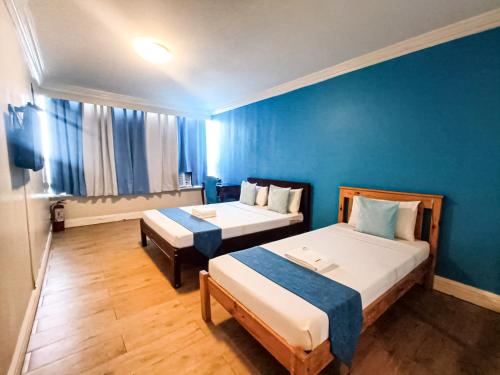 马尼拉Manila Airport Hotel by Urban Connect的一间设有两张床和蓝色墙壁的客房
