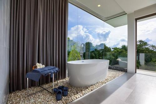 苏梅岛So Paradise Villa 4 bedrooms的一间带大浴缸和大窗户的浴室