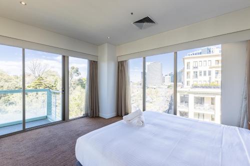 墨尔本四季植物园公寓式酒店的卧室设有白色的床和大窗户
