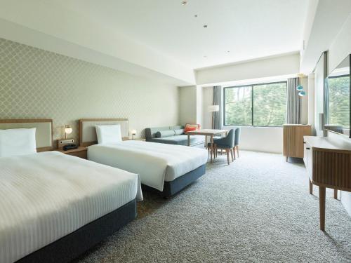 柏市Mitsui Garden Hotel Kashiwa-no-ha Park Side - Chiba的酒店客房设有两张床和一张桌子。