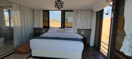 ShāhiqOman desert private camp的窗户客房内的一张大白色床