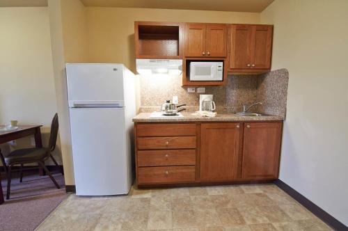 普莱森顿Savannah Suites Pleasanton的厨房配有白色冰箱和木制橱柜。