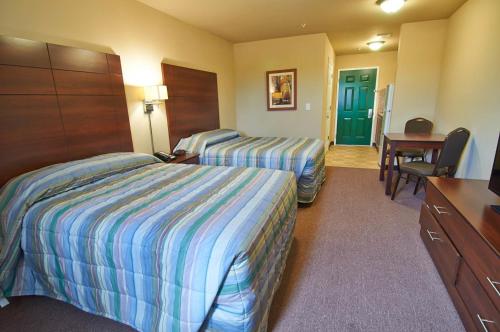 普莱森顿Savannah Suites Pleasanton的酒店客房配有两张床和一张书桌