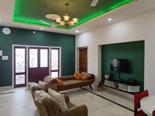 古瓦哈提Mulberry Guesthouse的客厅设有绿色的墙壁、沙发和电视。