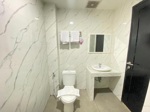 帕卢Urbanview Hotel Medio Inn Palu by RedDoorz的白色的浴室设有卫生间和水槽。
