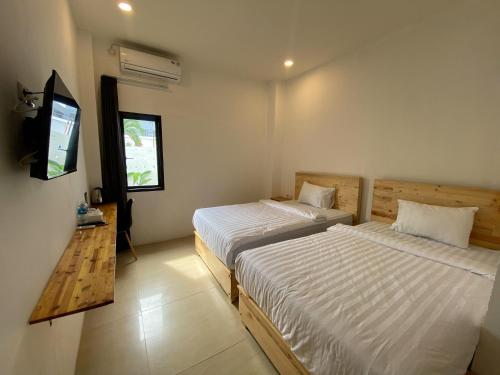 帕卢Urbanview Hotel Medio Inn Palu by RedDoorz的一间卧室配有两张床和电视。