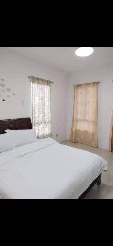 General TriasVacation home in Lancaster new city Cavite Philippines的卧室设有一张白色大床和两个窗户。