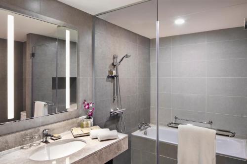 普崇Hilton Garden Inn Puchong的一间带水槽、浴缸和镜子的浴室
