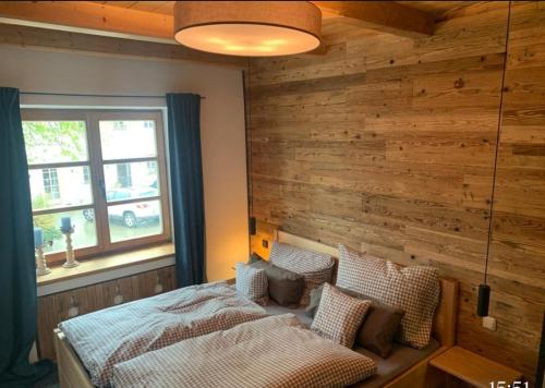 DietramszellMoarhof Ferienwohnung1的一间卧室设有木墙和一张带枕头的床。