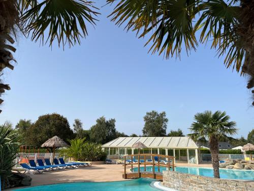 富埃南Camping de la Plage de Cleut-Rouz的一个带游泳池、椅子和棕榈树的度假村